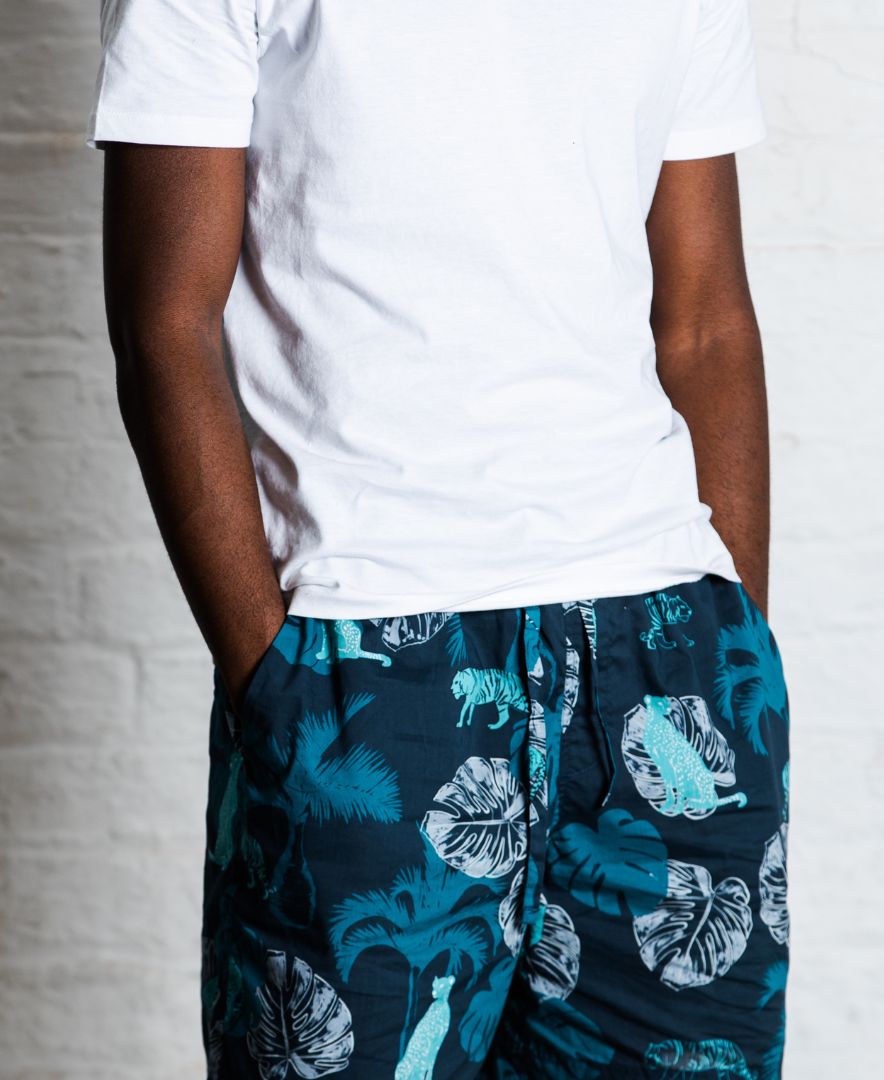 Model wearing The Tropics blue mens pyjama bottoms and white organic cotton white pyjama top